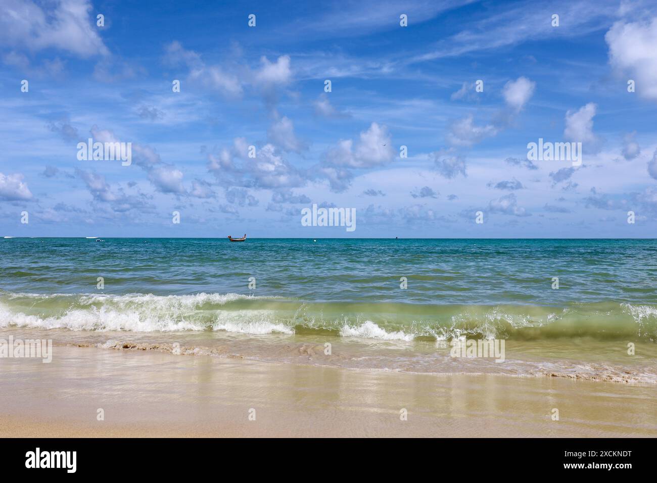 Spiaggia di sabbia marina vuota, vista pittoresca delle onde verde smeraldo e cielo blu con nuvole Foto Stock