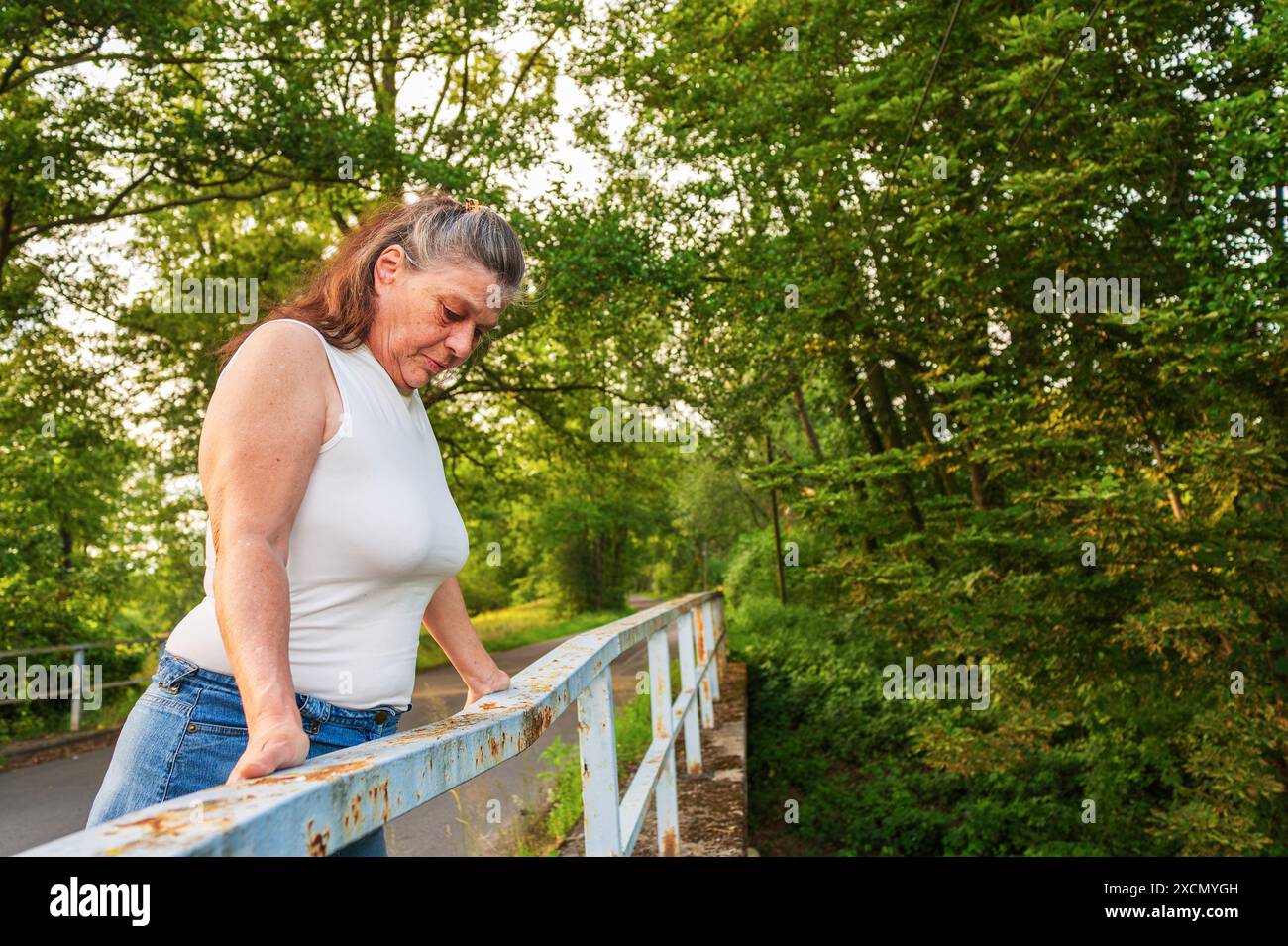 Una donna di oltre 60 anni si trova sulla ringhiera di un ponte Foto Stock