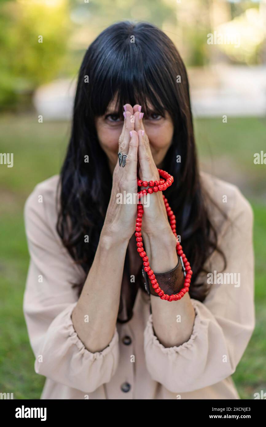 Donna che tiene un japa mala all'aperto mentre guarda la macchina fotografica. Scatto verticale Foto Stock