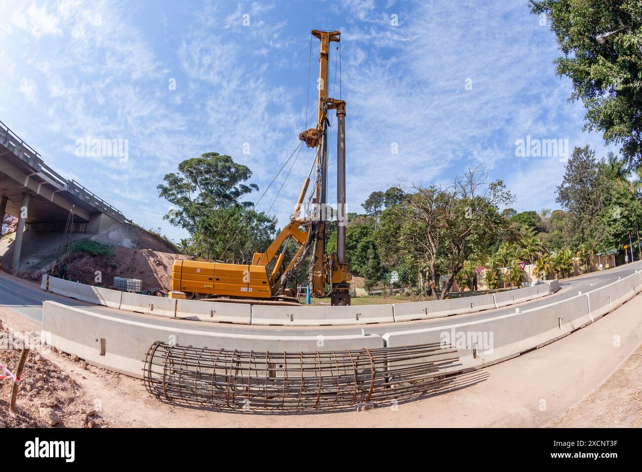 Ampliamento dei ponti per le corsie autostradali. Perforazione di ingegneria industriale con macchinari per gru pesanti per nuovi coni in acciaio con calcestruzzo nel foro di terra Foto Stock