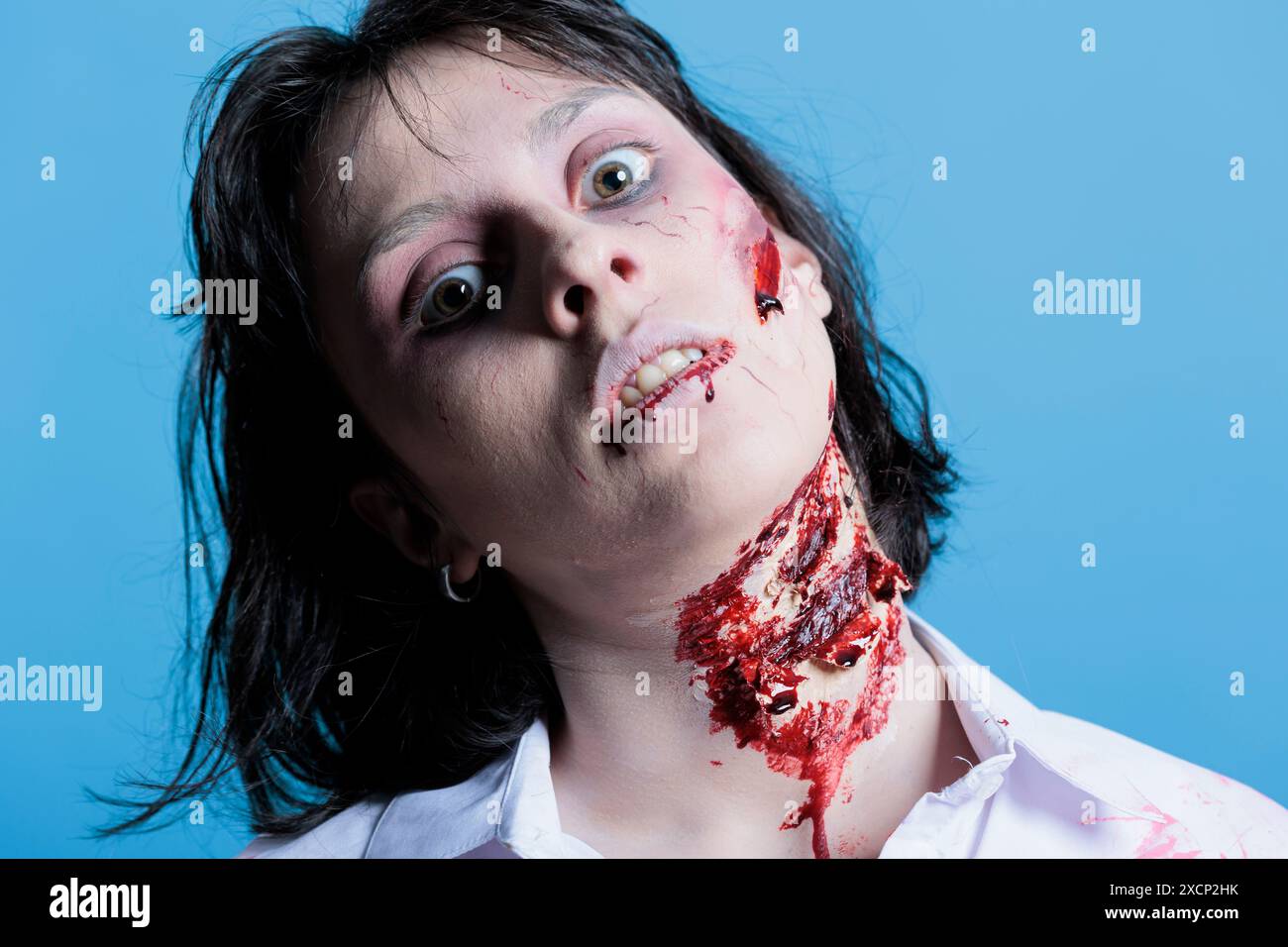 Ritratto di una donna posseduta con occhi raccapriccianti coperti di sangue, che si trasforma in zombie dopo essere stata uccisa. Cadavere ferito ferito spettrale infettato da virus che si trasforma in mostro, sfondo studio Foto Stock