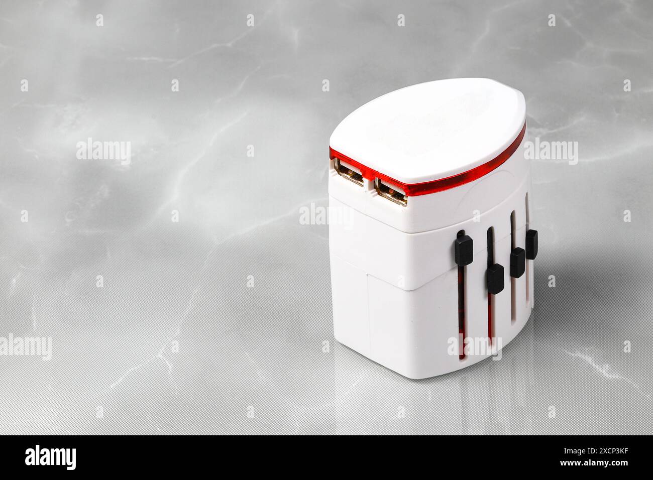 Adattatore universale, adattatore da viaggio isolato sulla superficie riflettente. Foto Stock