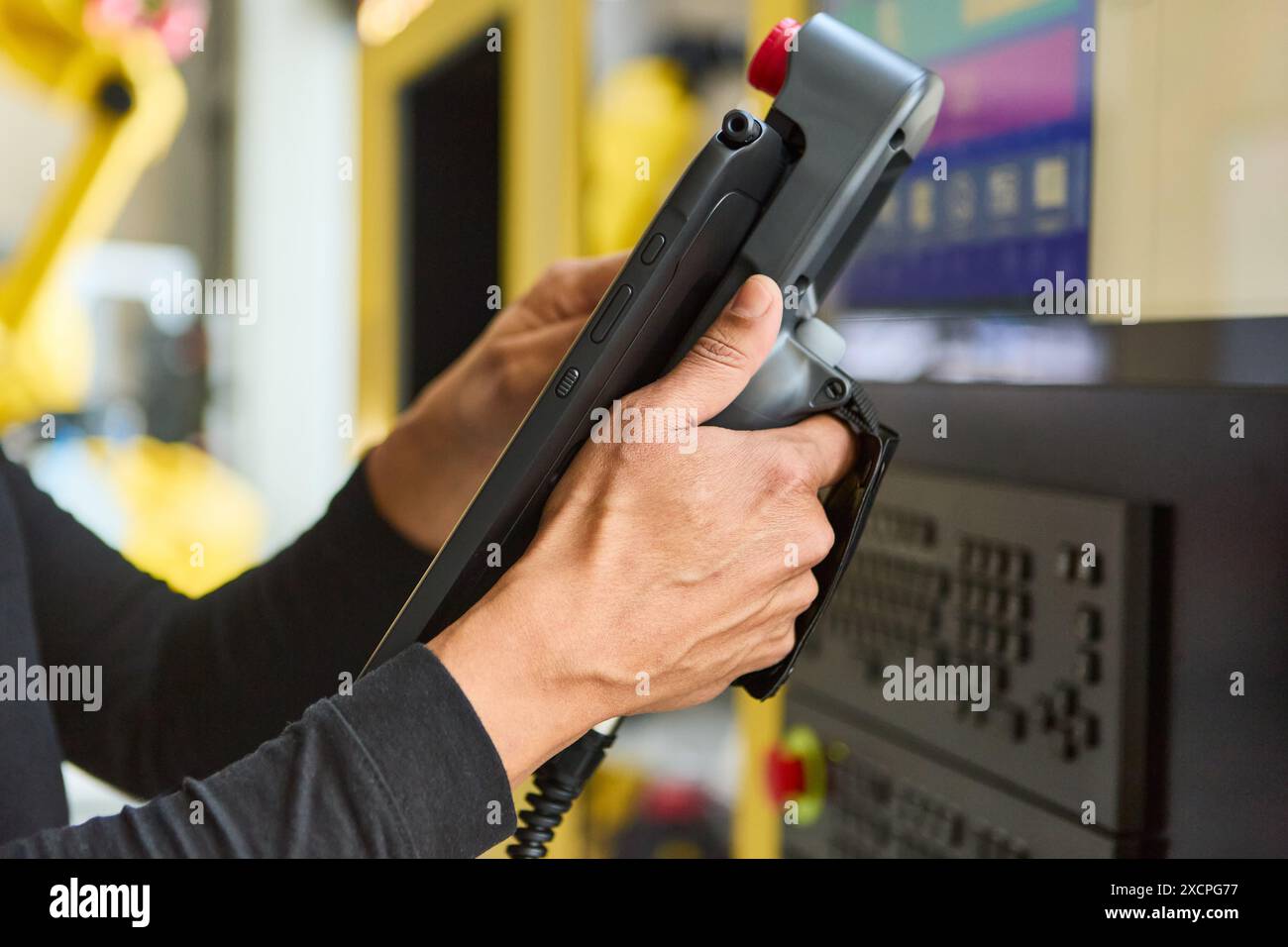 Ingegnere che utilizza un tablet per programmare e controllare un braccio robotico per applicazioni industriali in un ambiente di laboratorio tecnologico. Foto Stock