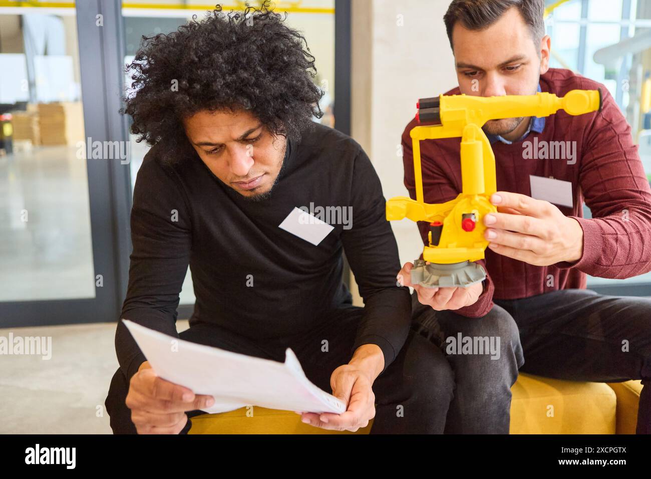 Due ingegneri che lavorano allo sviluppo e alla progettazione di un braccio di presa robotizzato per applicazioni industriali, concentrandosi sull'innovazione, l'automazione dei processi, Foto Stock