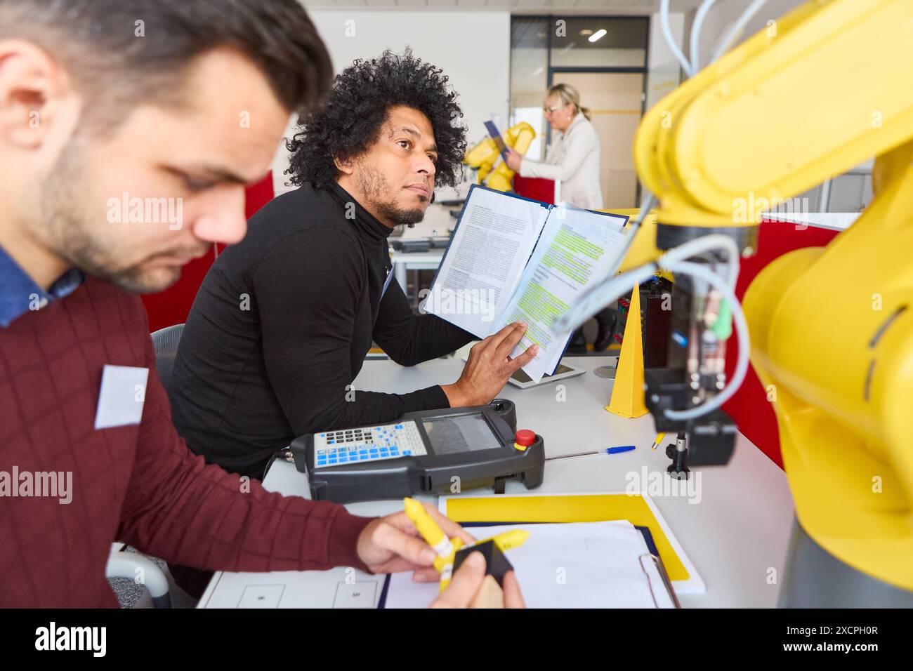 Gli ingegneri si impegnano nella programmazione di bracci robotici industriali durante una sessione di formazione. Concentratevi sulla robotica, l'automazione e la formazione tecnologica. Foto Stock