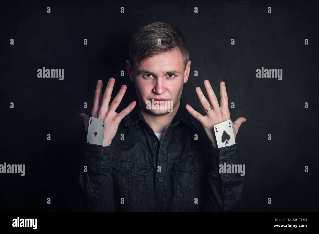 Giocatore d'azzardo sicuro e insidioso con assi in manica. Illusionista che mostra trucchi con carte da gioco isolate su sfondo scuro. Giochi d'azzardo, fortuna e del Foto Stock