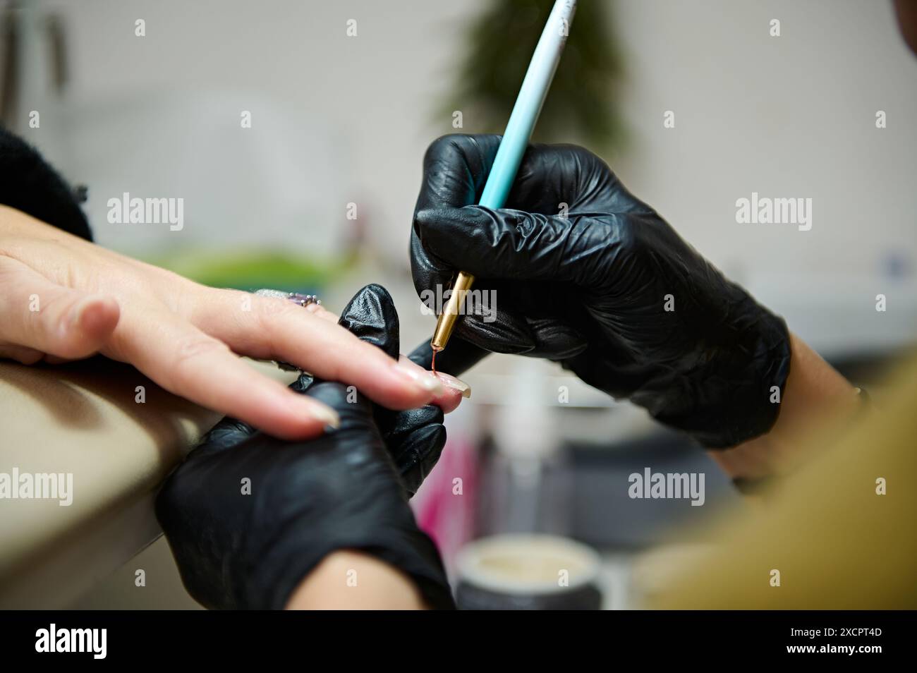 Primo piano di un tecnico di unghie che applica nail art in un salone di bellezza. Perfetto per illustrare bellezza, stile e servizi di manicure professionali. Foto Stock