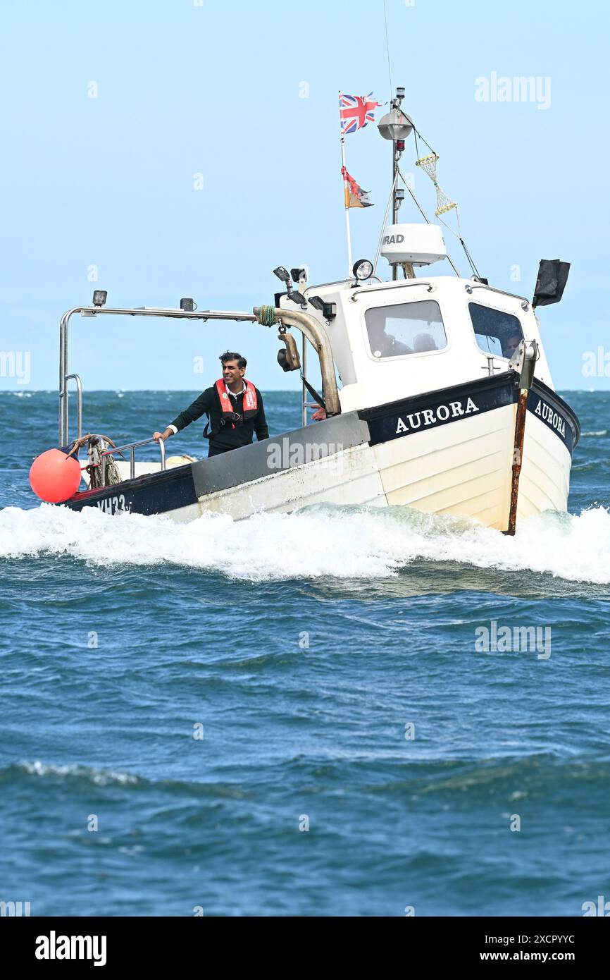 Il primo ministro Rishi Sunak cavalca su una barca nel porto di Clovelly, mentre raccoglie le pentole di aragosta, durante una visita nel Devon settentrionale, mentre si trovava sulle tracce della campagna elettorale generale. Data foto: Martedì 18 giugno 2024. Foto Stock