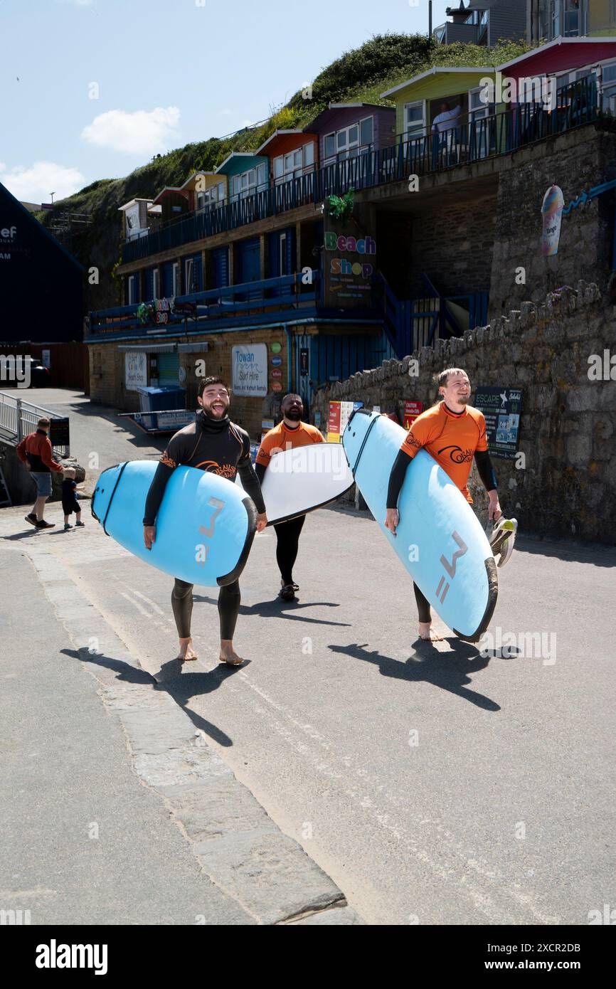 Un istruttore di surf della Cornish Wave Surf School e due studenti che portano le loro tavole da surf dopo una lezione di surf a Towan Beach a Newquay in Foto Stock