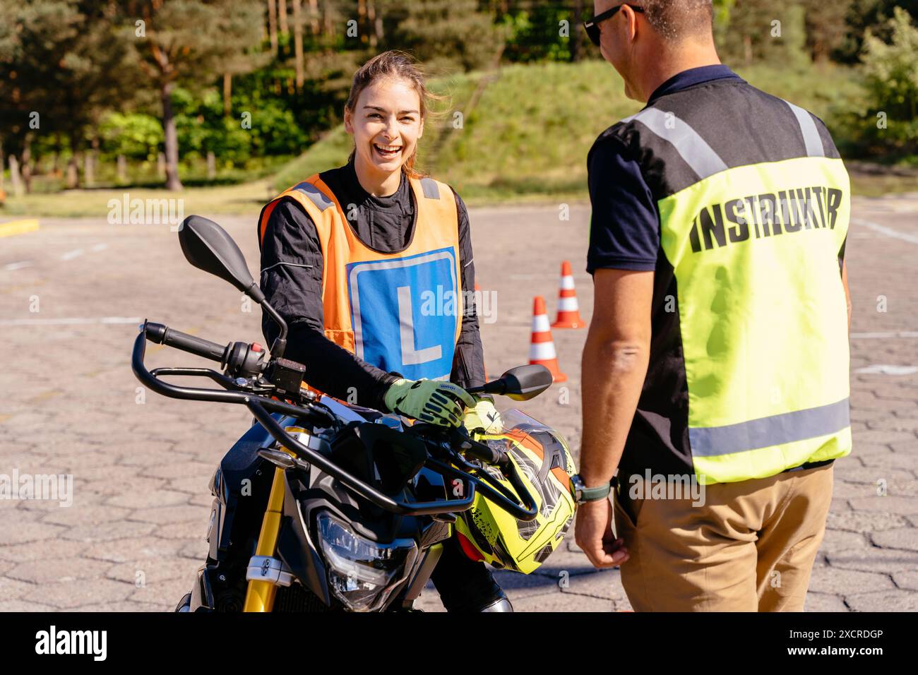 Primo piano di un istruttore di guida maschile che mostra i comandi e il cruscotto della motocicletta a una studentessa inesperta. Imparare a guidare il concetto di motocicletta Foto Stock