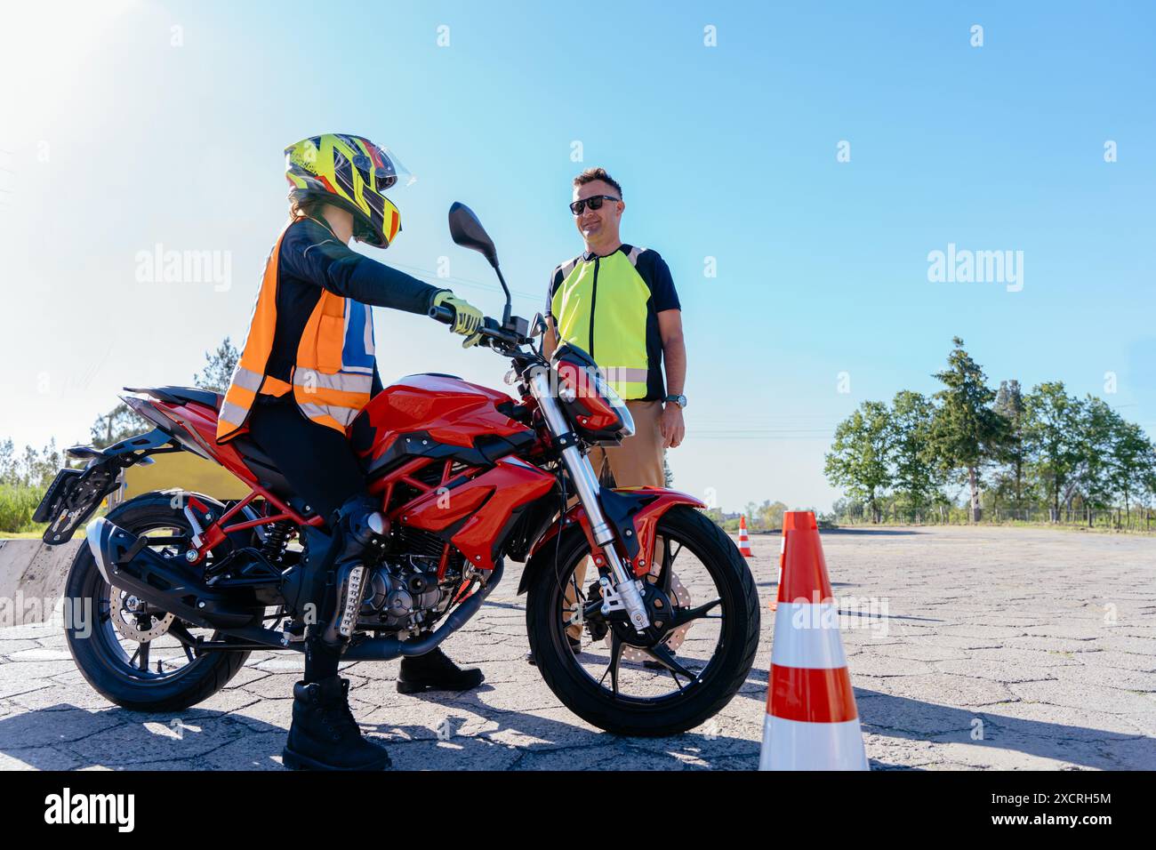 Istruttore di guida che mostra i comandi e il cruscotto della motocicletta allo studente inesperto. Imparare a guidare la moto. Foto Stock