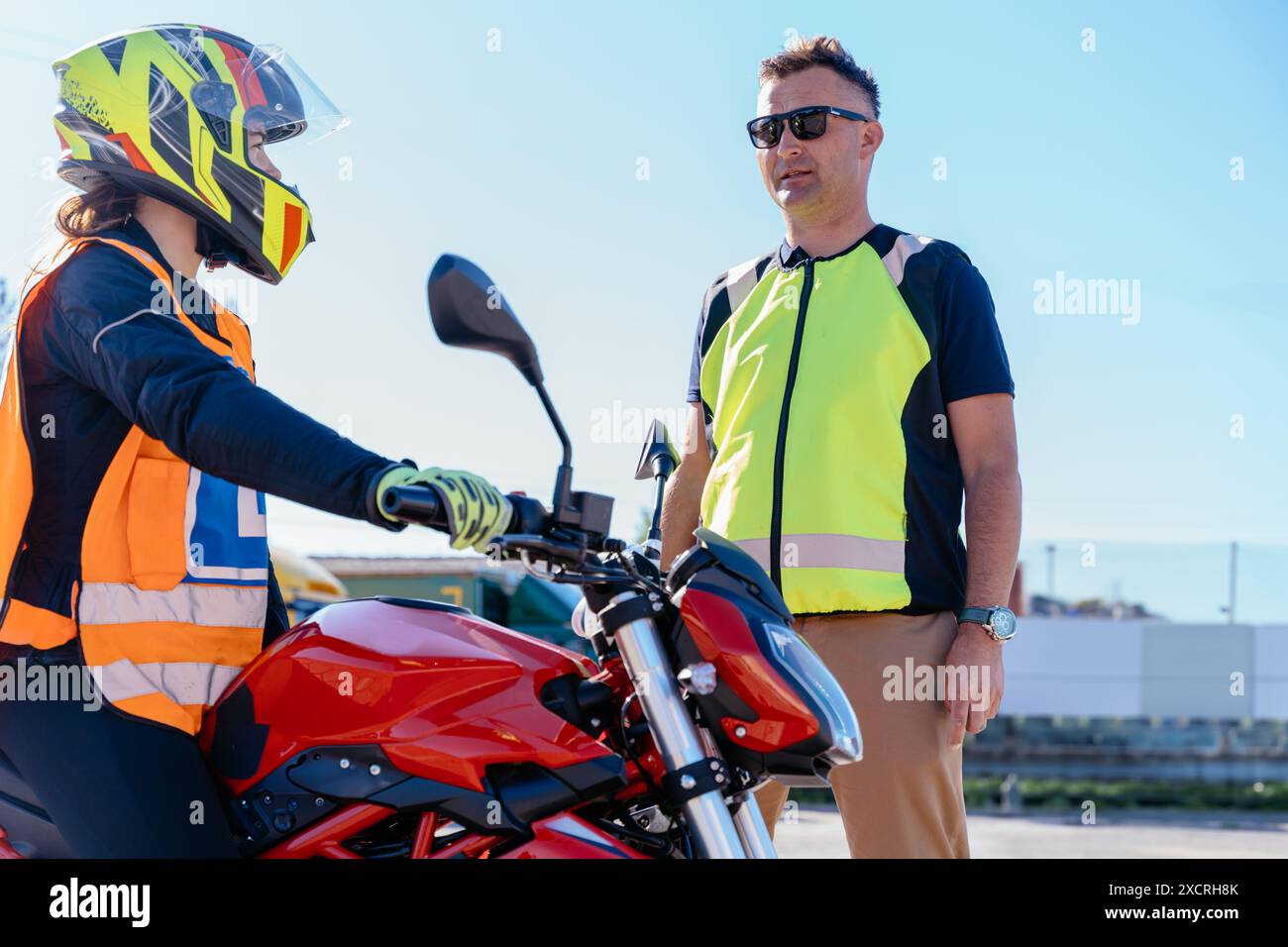 Istruttore di guida che mostra i comandi e il cruscotto della motocicletta allo studente inesperto. Imparare a guidare la moto. Foto Stock