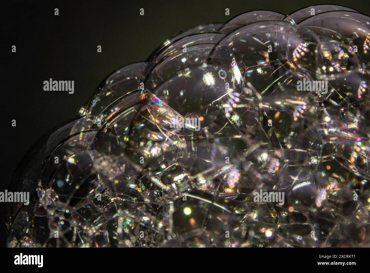 Macro astratta primo piano di bolle che soffiano più piccole bolle con sfondo nero e forme e riflessi colorati. Foto Stock