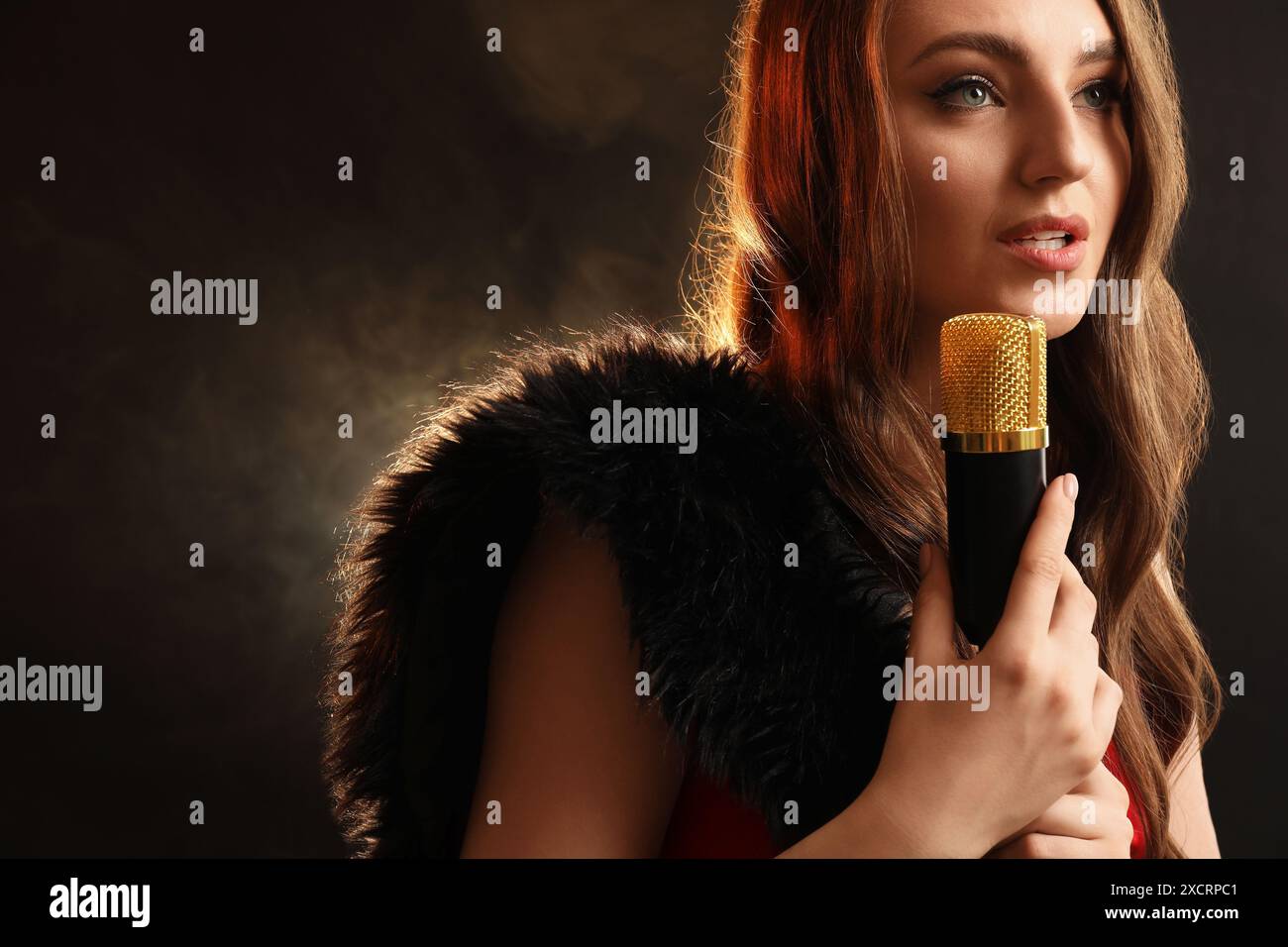 Bella giovane cantante jazz con microfono su sfondo scuro e fumo. Spazio per il testo Foto Stock