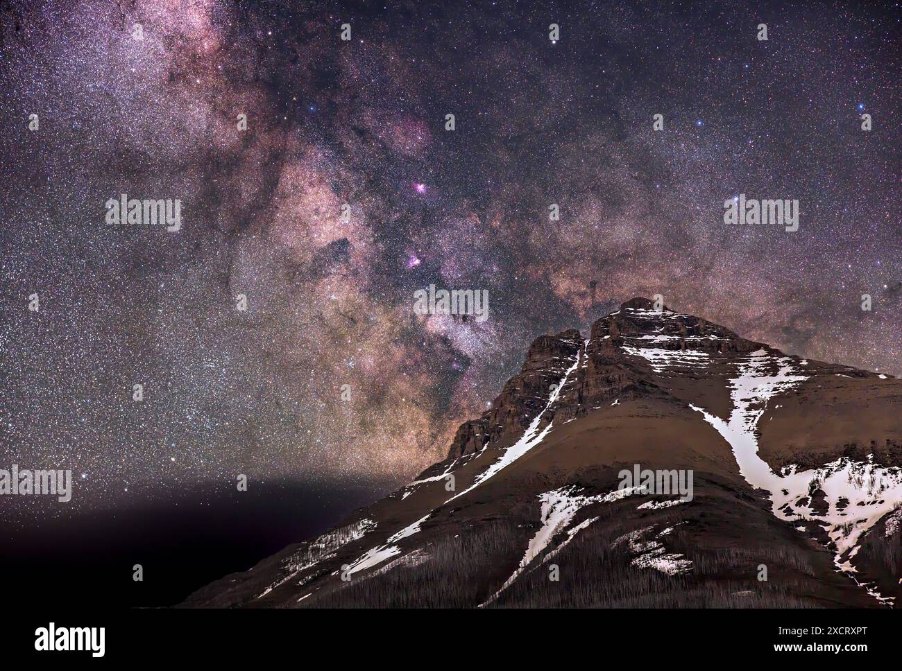 La via Lattea che si innalza sulla cima del Monte Blakiston, nel Waterton Lakes National Park, Alberta, Canada. Questo era il 10/11 giugno 2024, quindi un po' di neve ancora r Foto Stock