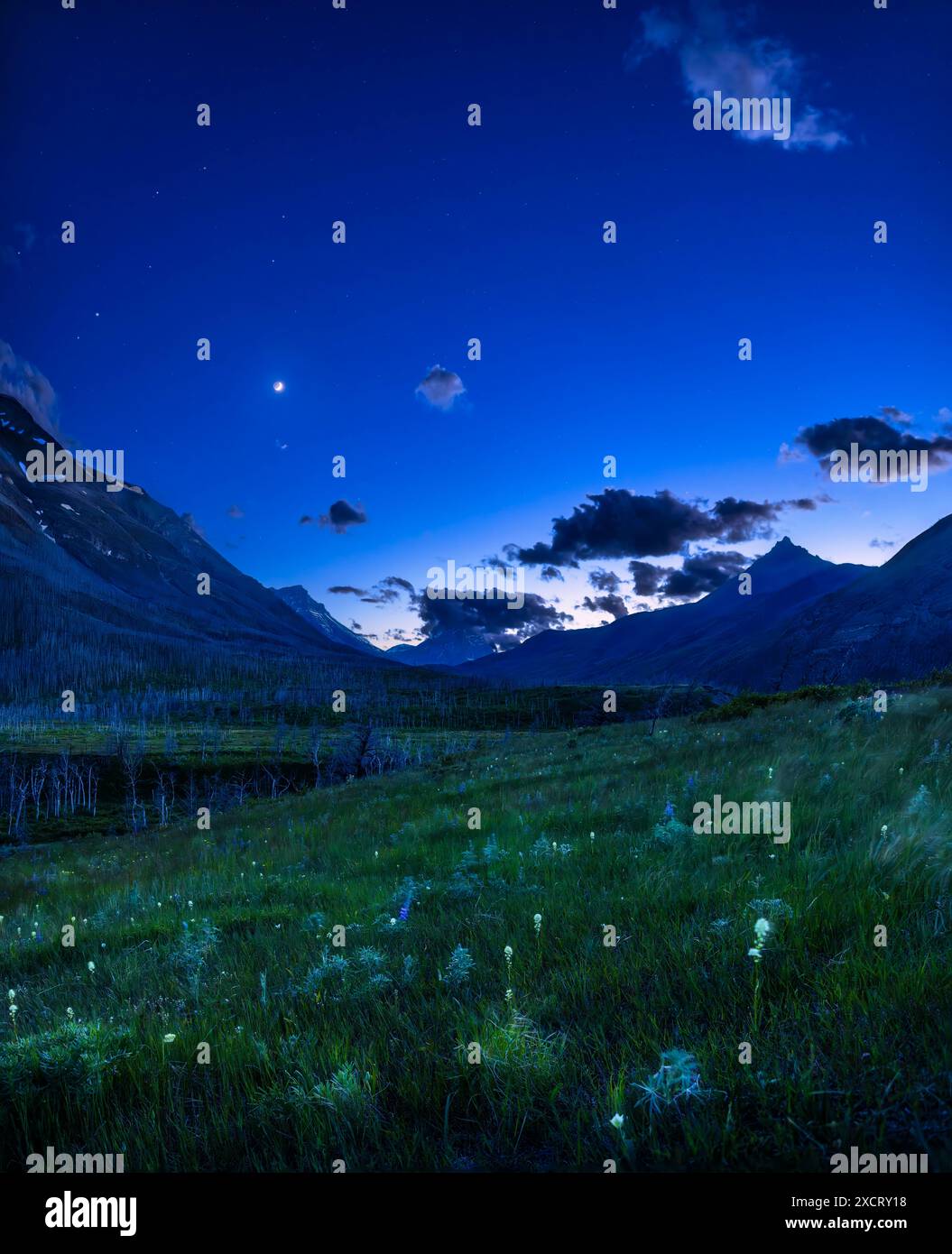 Una scena notturna sotto un cielo di "ora blu" al crepuscolo, sulla Red Rock Canyon Road nel Waterton Lakes National Park, Alberta, guardando verso ovest verso il sole Foto Stock