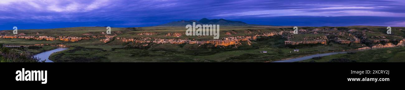 Un panorama del paesaggio di arenaria al crepuscolo di ora blu al Writing-on-Stone Provincial Park (Áísínai'pi) in Alberta, con il fiume Milk sottostante che vince Foto Stock