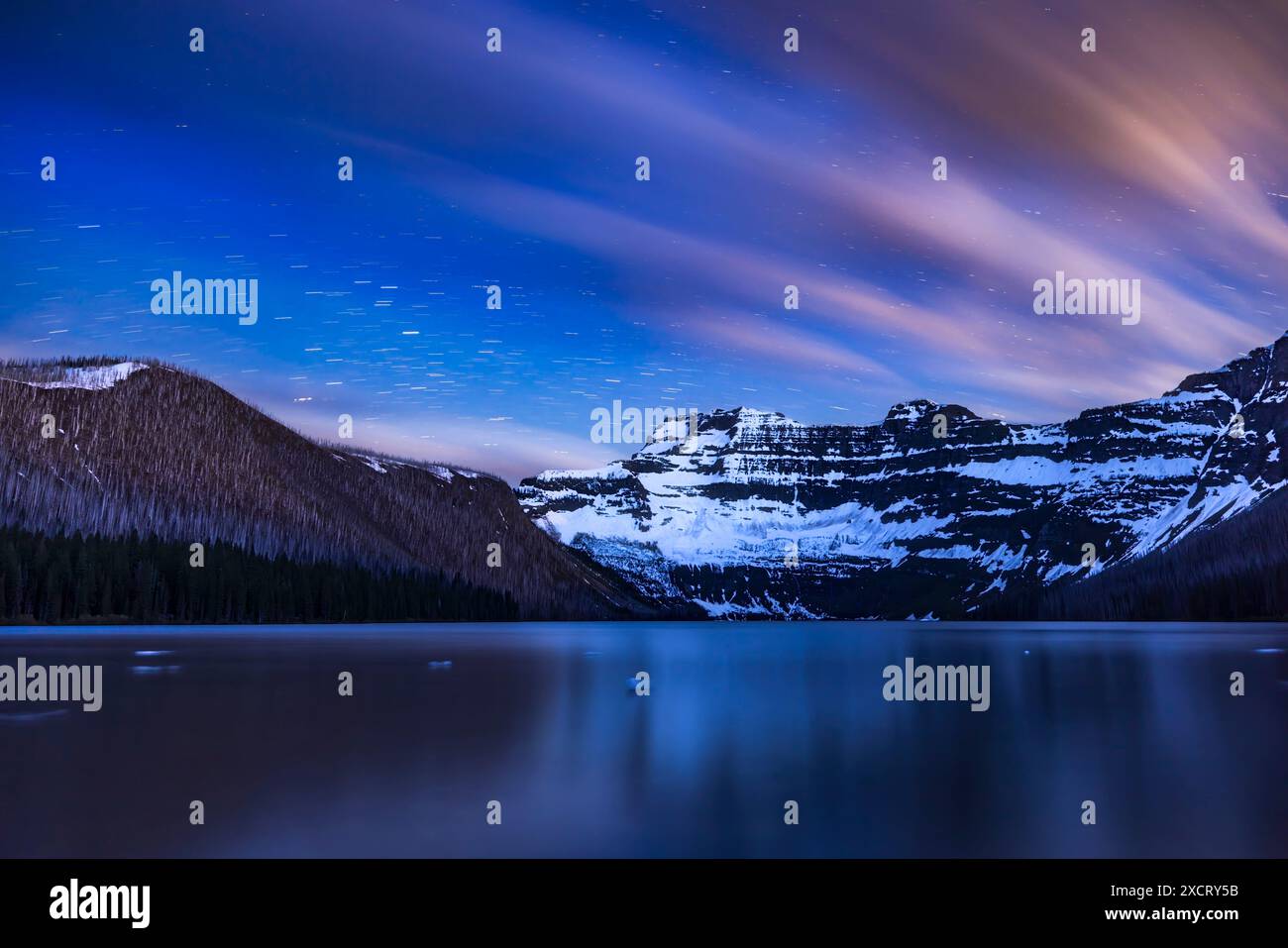 Le stelle e le nuvole si snodano attraverso il cielo sopra il lago Cameron nel Waterton Lakes National Park, Alberta e Mt. Custer oltre il confine nel Glacier nati Foto Stock