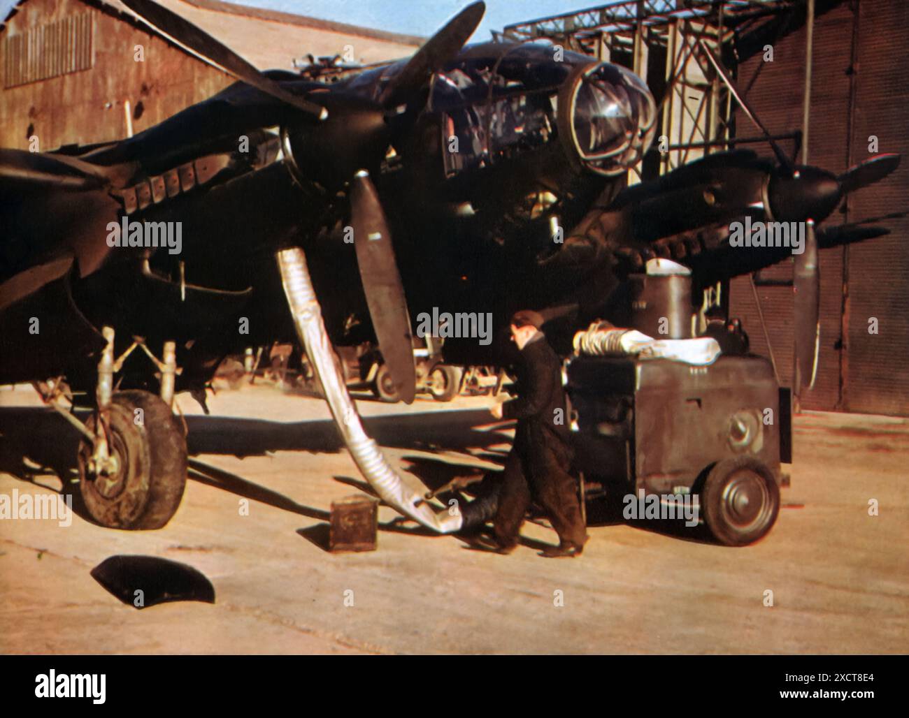 Una fotografia cattura un meccanico dell'Aeronautica tedesca (Luftwaffe) che preriscalda i motori degli aerei prima di un volo durante la seconda guerra mondiale. Il preriscaldamento è stato fondamentale per garantire prestazioni ottimali del motore ed evitare guasti meccanici, soprattutto a basse temperature. Gli aerei ad elica, pur essendo affidabili, avevano limitazioni come la necessità di una manutenzione più frequente e la preparazione prima del volo. Foto Stock