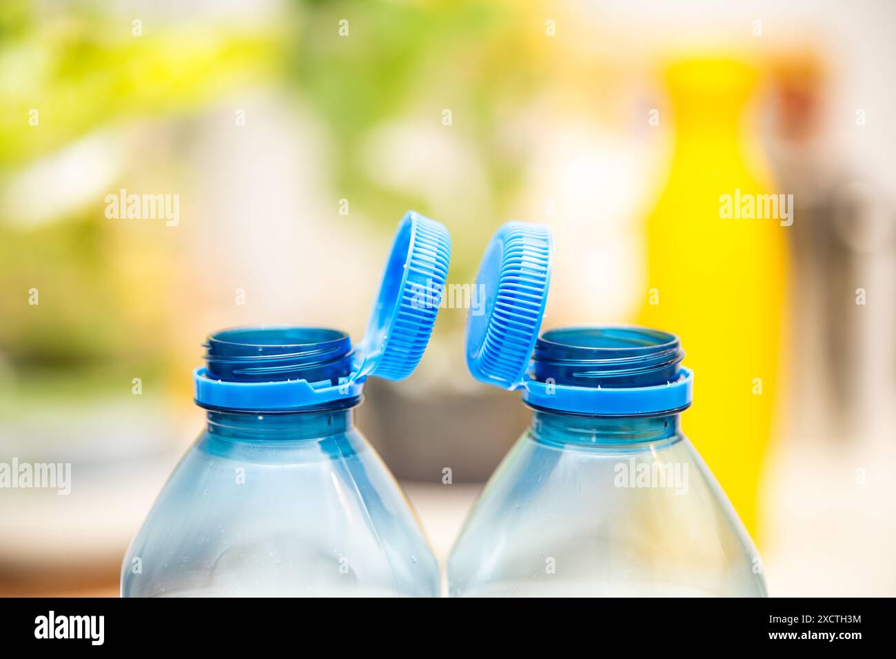 L'immagine cattura i tappi blu fissati su bottiglie di plastica trasparente, riflettendo gli sforzi per la sostenibilità ambientale previsti dalla direttiva UE Foto Stock