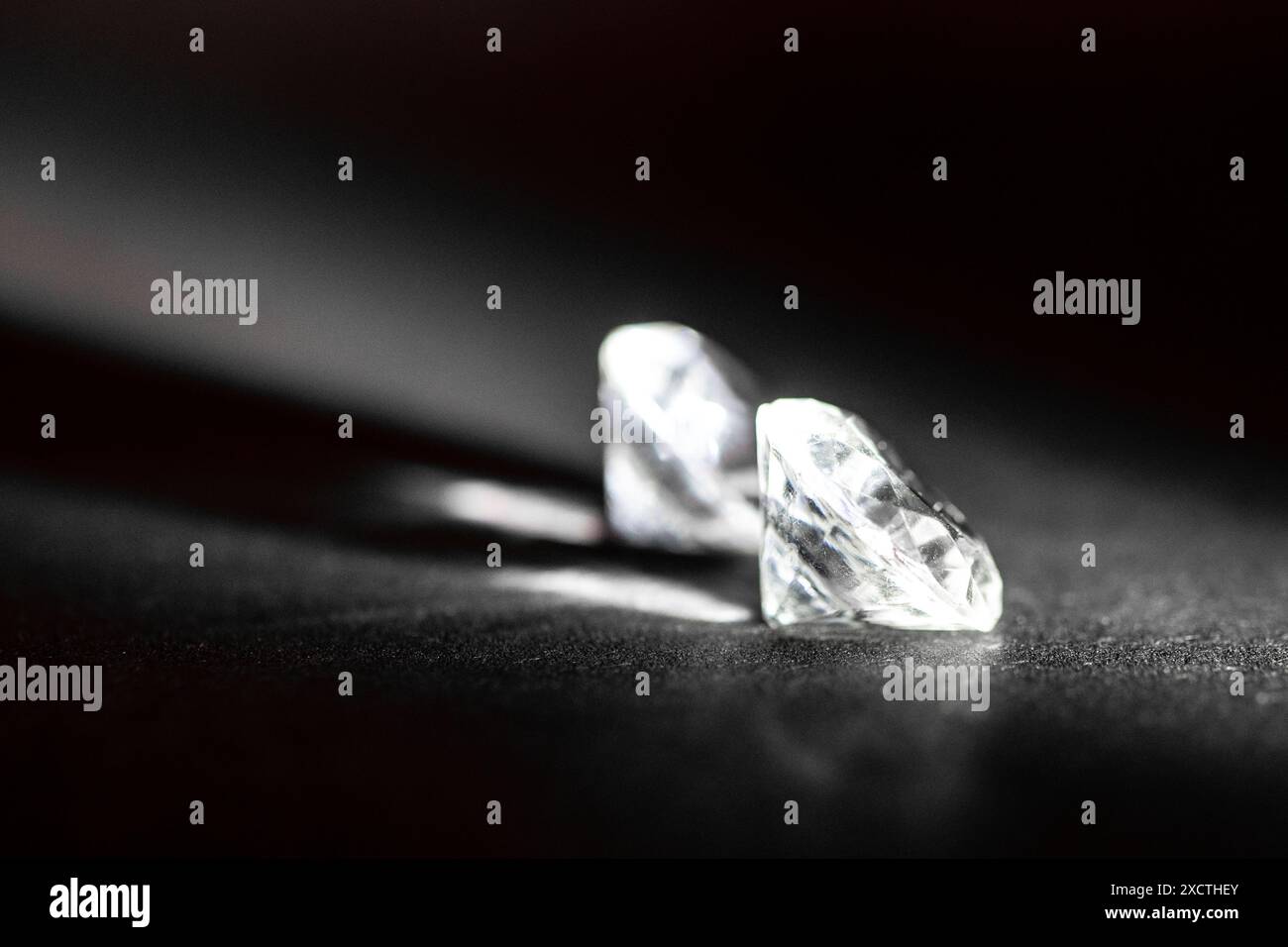 Due lussuosi diamanti dal taglio brillante si trovano elegantemente su una superficie scura, illuminati delicatamente per migliorare la loro nitidezza sorprendente, le sfaccettature complesse e il lusso Foto Stock