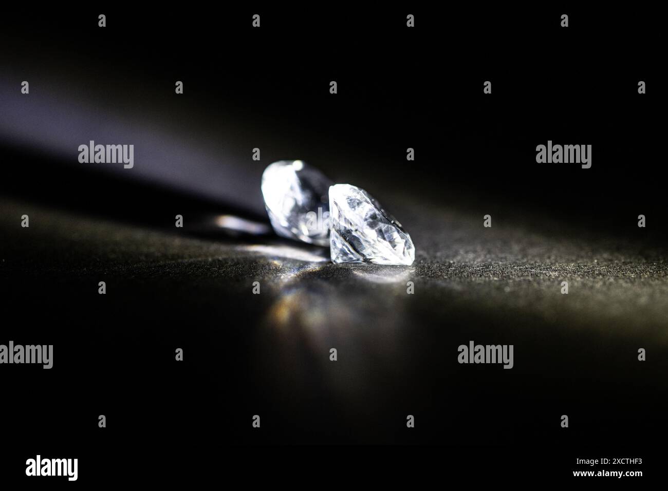 Due diamanti immacolati e smontati proiettano un bagliore radioso su uno sfondo ombroso, che incarna il lusso e il mercato di fascia alta. Lusso nascosto Foto Stock