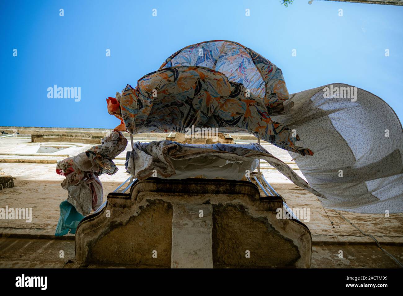 L'affascinante balcone dell'Italia meridionale con le lenzuola che pendono dal balcone ondeggiano dolcemente nel vento, creando bellissime curve fluenti Foto Stock
