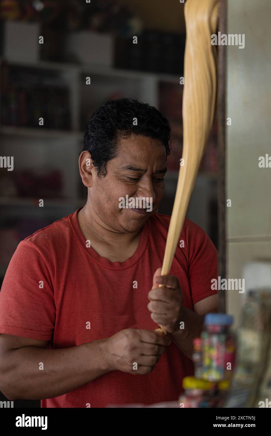 L'uomo latino si vede realizzare a mano le tradizionali caramelle Melcocha a Baños de Agua Santa, Ecuador. Questo processo artigianale mette in risalto il patrimonio culturale e. Foto Stock