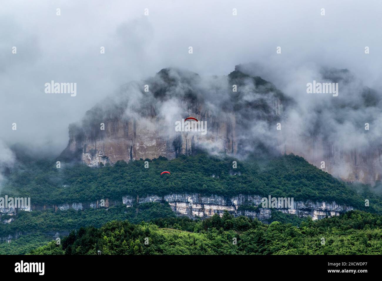 CHONGQING, CINA - 18 GIUGNO 2024 - i turisti sorvolano il sito Patrimonio naturale dell'Umanità del monte Jinfo su un parapendio presso la Jinfo Mountain Aviation Foto Stock