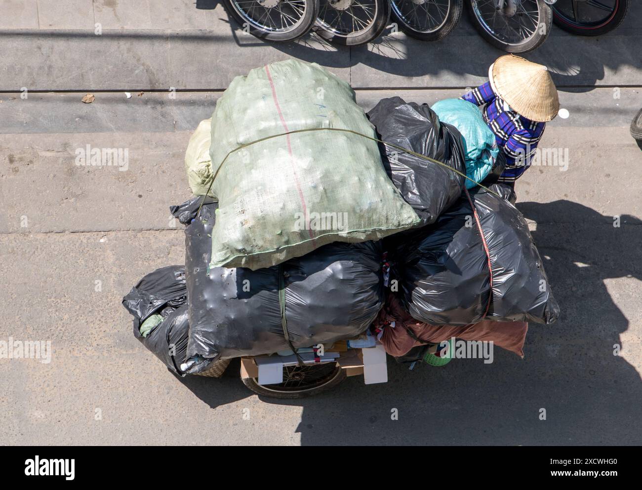 Raccolta di rifiuti riciclabili nelle strade della città di ho chi Minh. Gente vietnamita che spinge un carro pieno di borse, Saigon City. Foto Stock