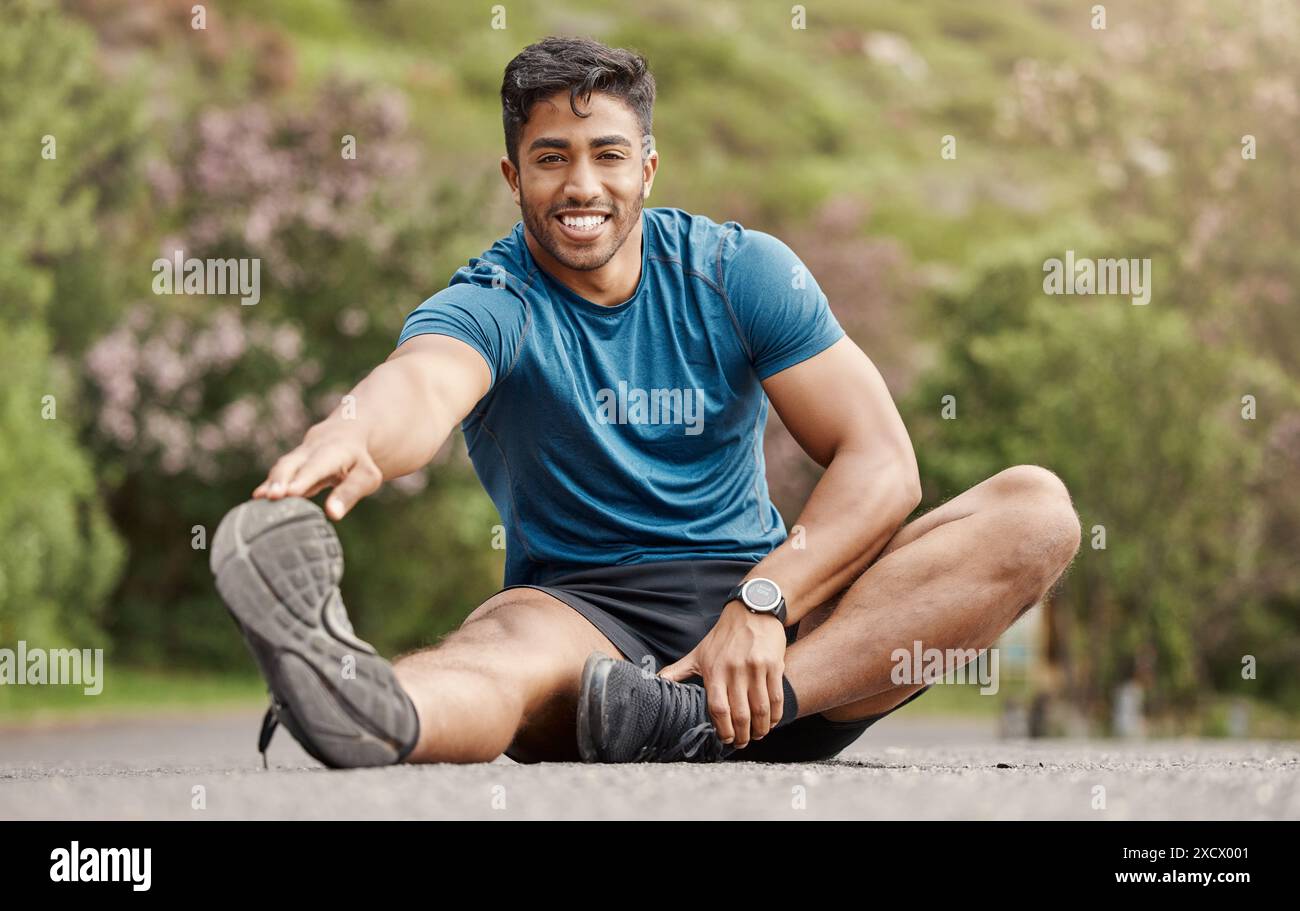 Uomo indiano, ritratto e stretching gamba per fitness, allenamento ed esercizio fisico per il benessere con equilibrio. All'aperto, su strada e uomo runner con riscaldamento Foto Stock