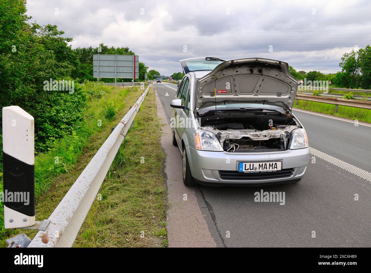 Un'auto in avaria si ferma sull'autostrada con un triangolo di pericolo e pericolo dietro di essa Foto Stock