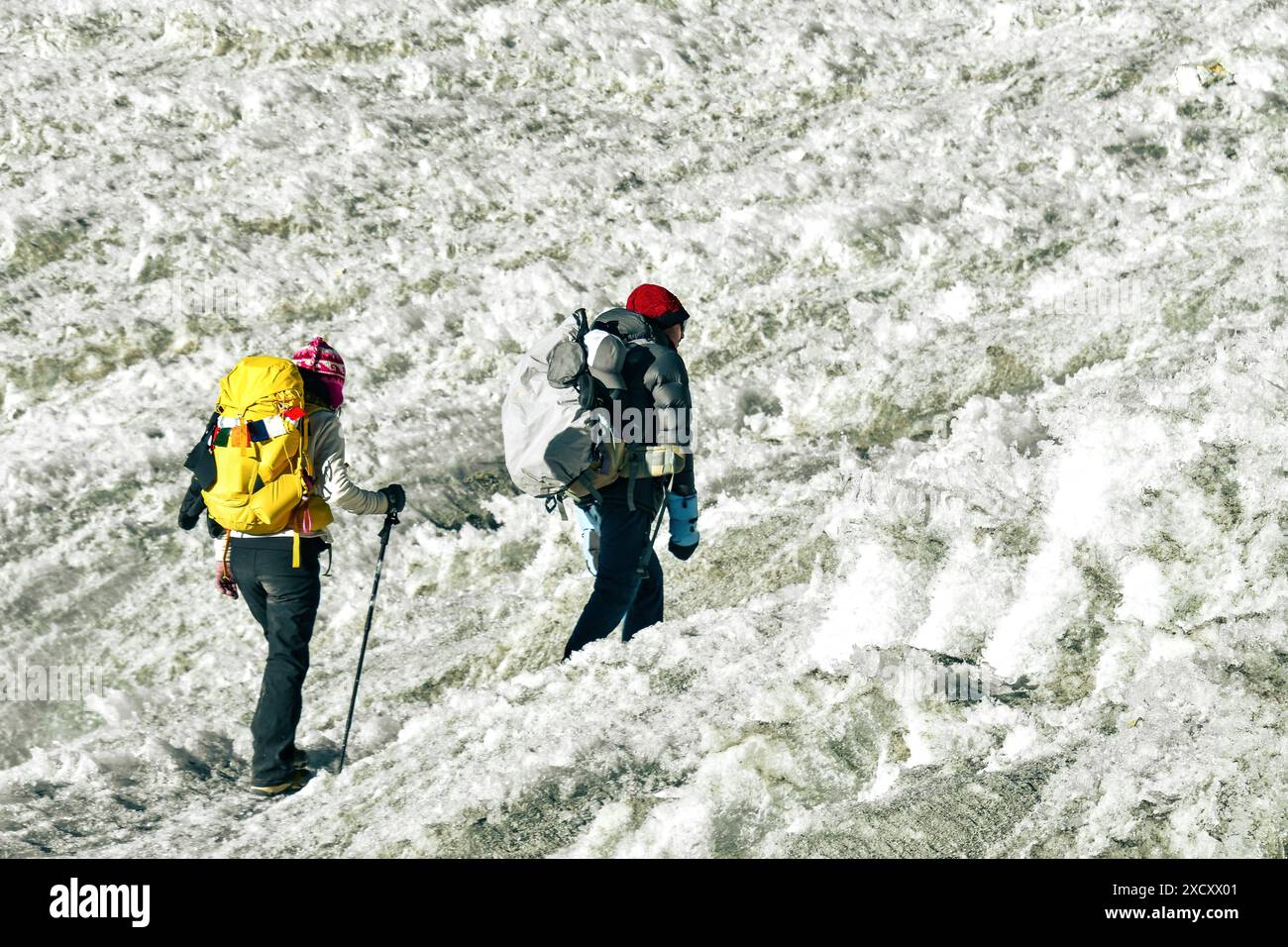 Due escursionisti fanno trekking sulle montagne dell'Himalaya attraverso il passo del ghiacciaio Chola fino a Gokyo Ri. Guida maschile nepalese, principale cliente turistico a Sagarmatha National Foto Stock