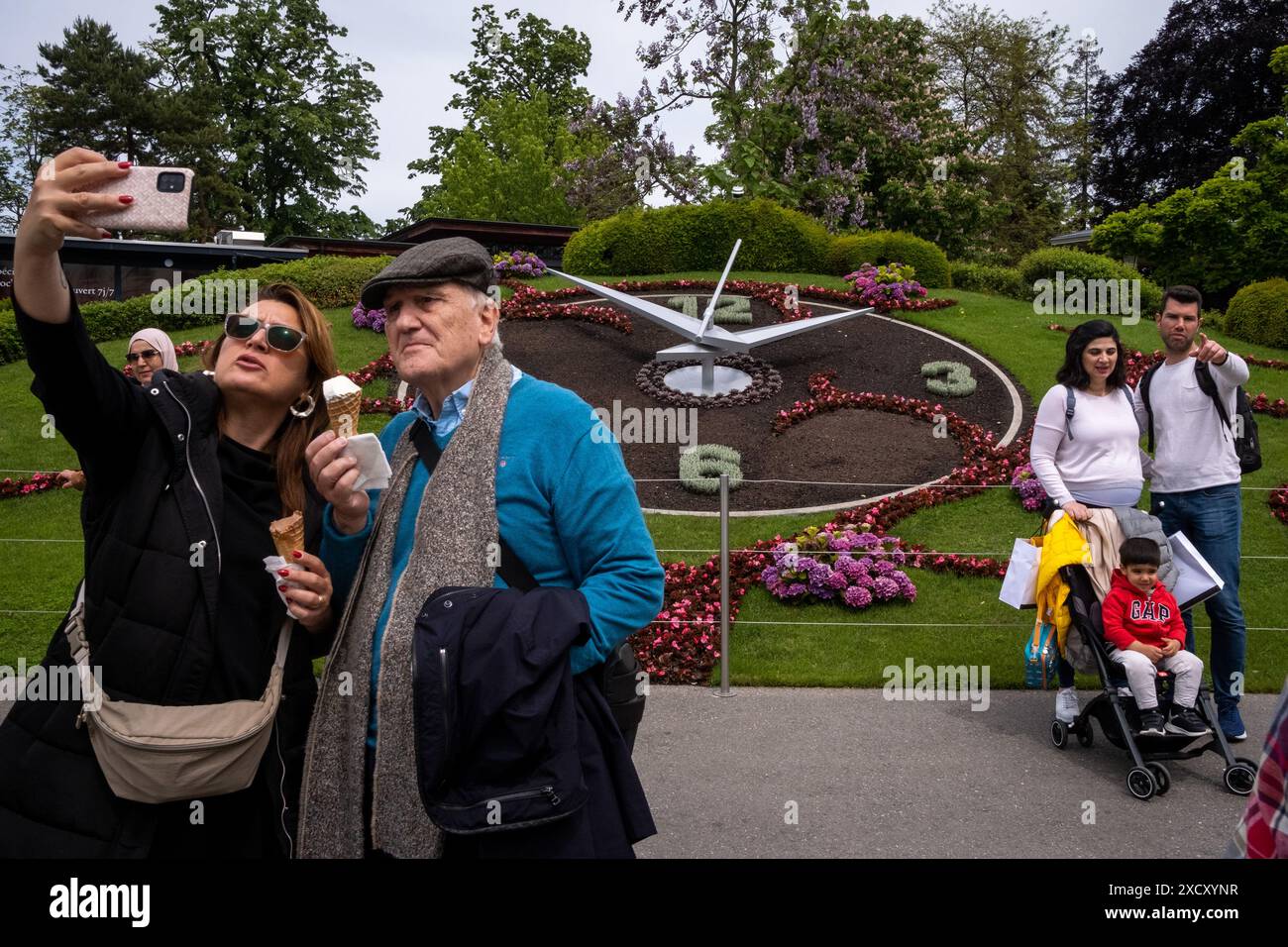 Una famiglia di turisti si fa un selfie di fronte all'Horloge Fleurie, un famoso orologio floreale all'aperto fatto di fiori colorati, nel Jardin Anglais Foto Stock