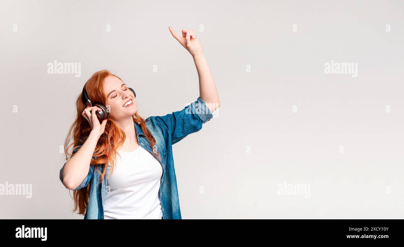 Giovane donna che ama la musica con le cuffie ballando con gioia Foto Stock