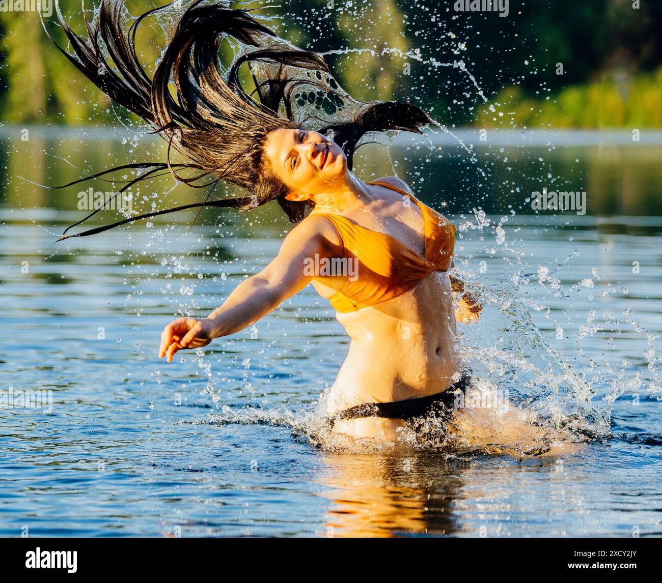 Donna dai capelli lunghi che spruzza nel lago Foto Stock