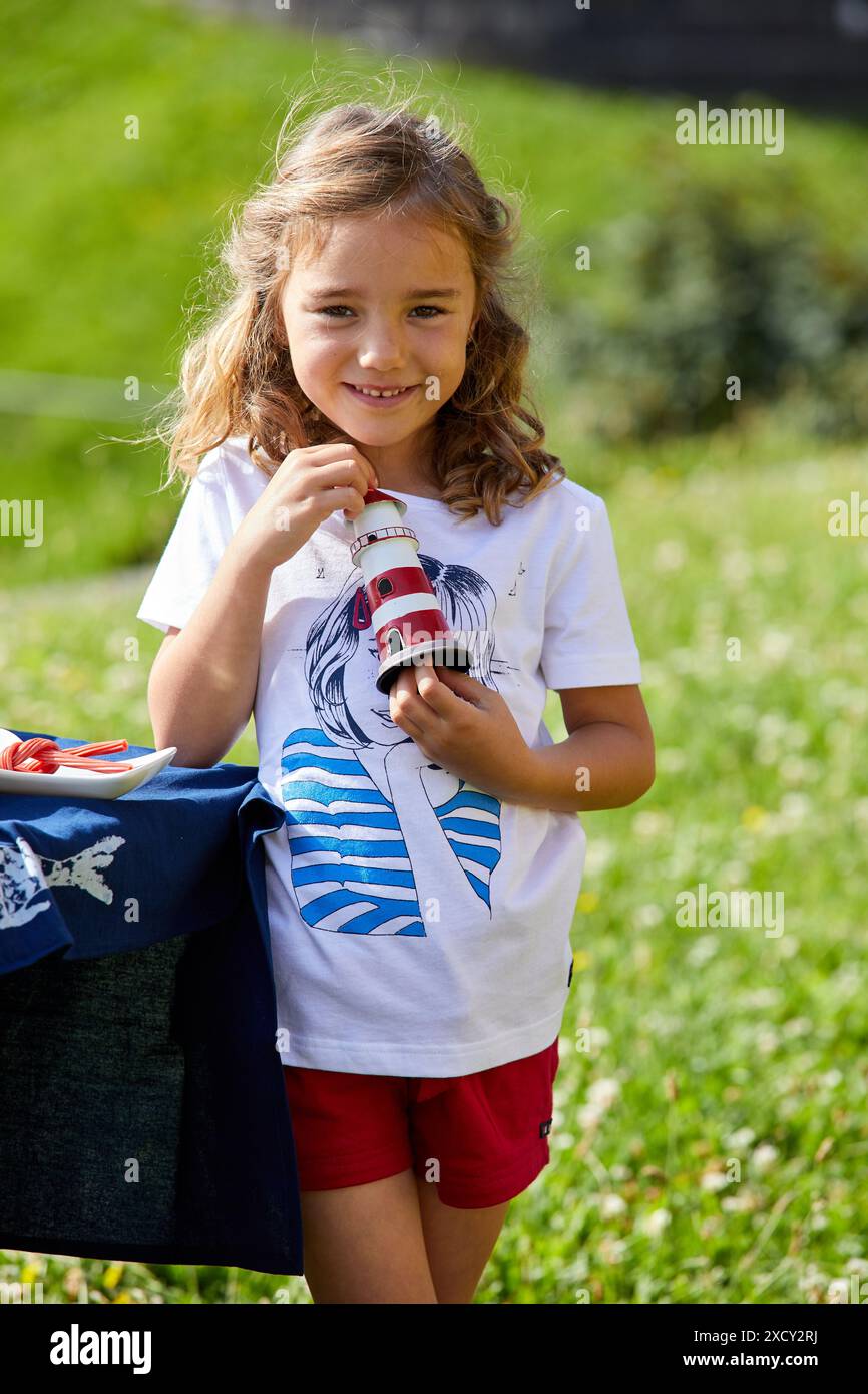 Ragazza con toy faro, guardando la telecamera, Getaria, Gipuzkoa, Paesi Baschi Foto Stock