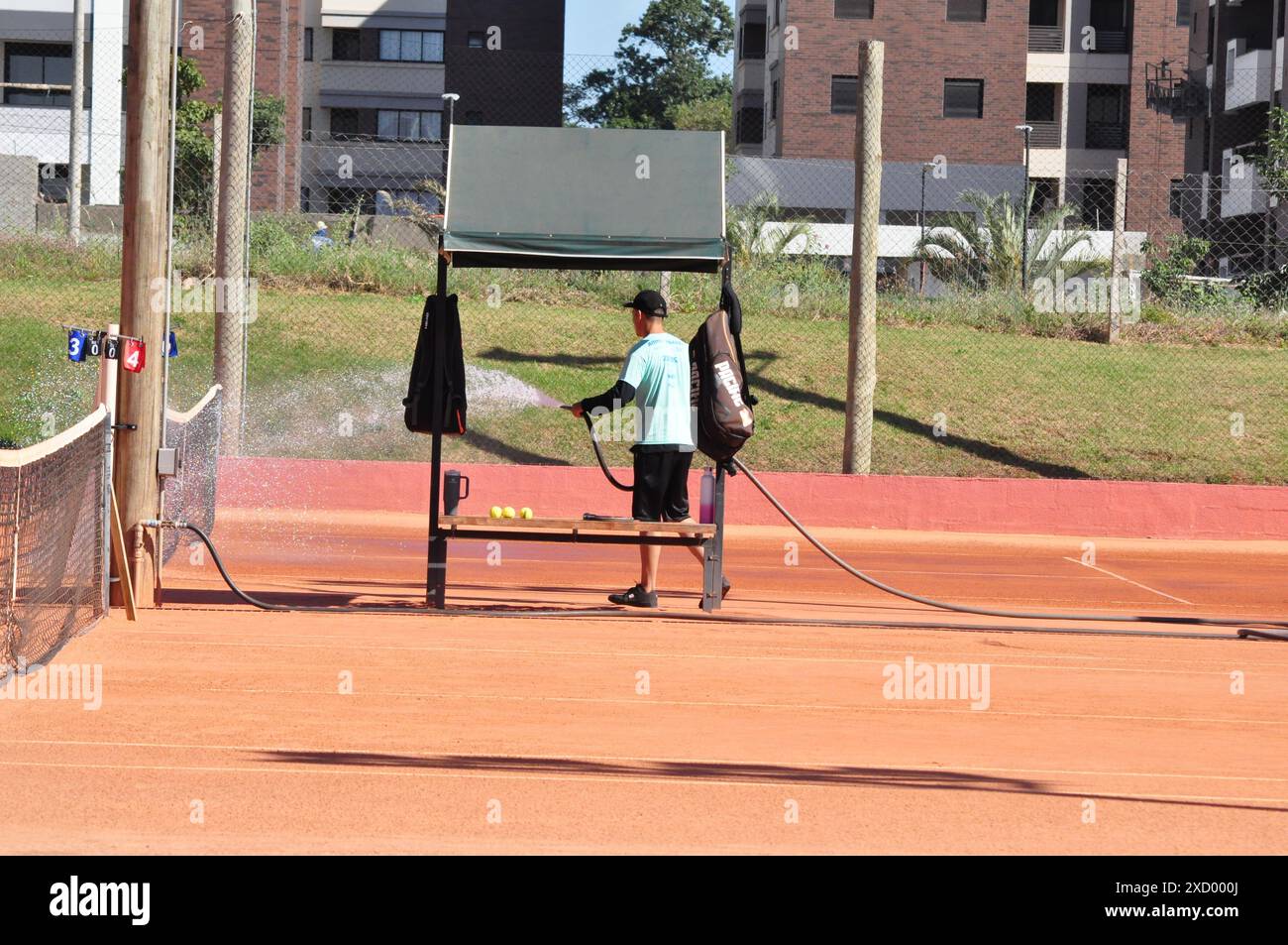 Il dipendente annaffierà il campo di argilla per una partita di tennis Foto Stock