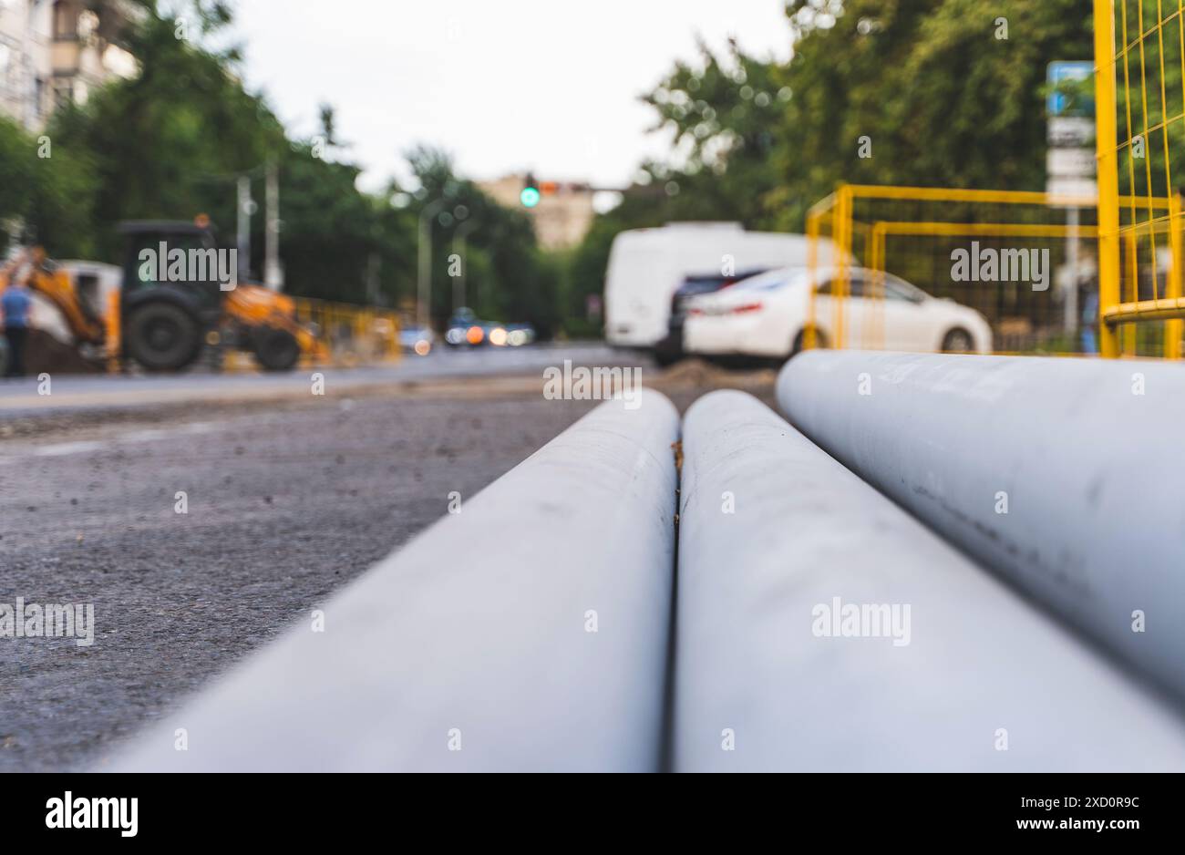 Lavori stradali. Ricostruzione delle tubature sotterranee su una strada della città. Nuovi tubi in metallo sulla strada. Foto Stock