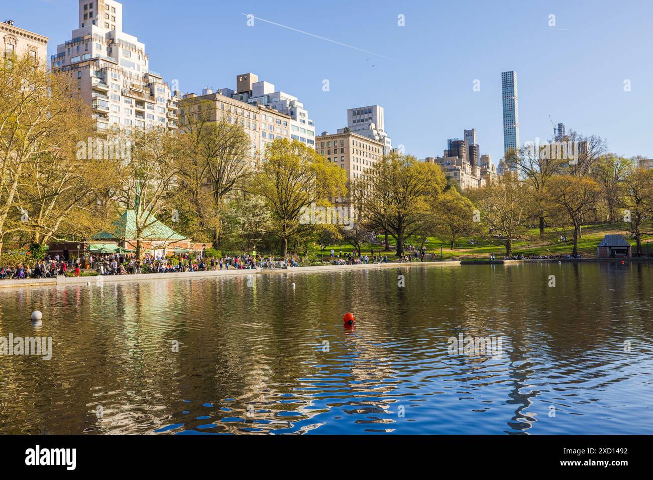 La gente cammina lungo i sentieri vicino al lago a Central Park, con i grattacieli di Manhattan che torreggiano sullo sfondo. New York. STATI UNITI. Foto Stock