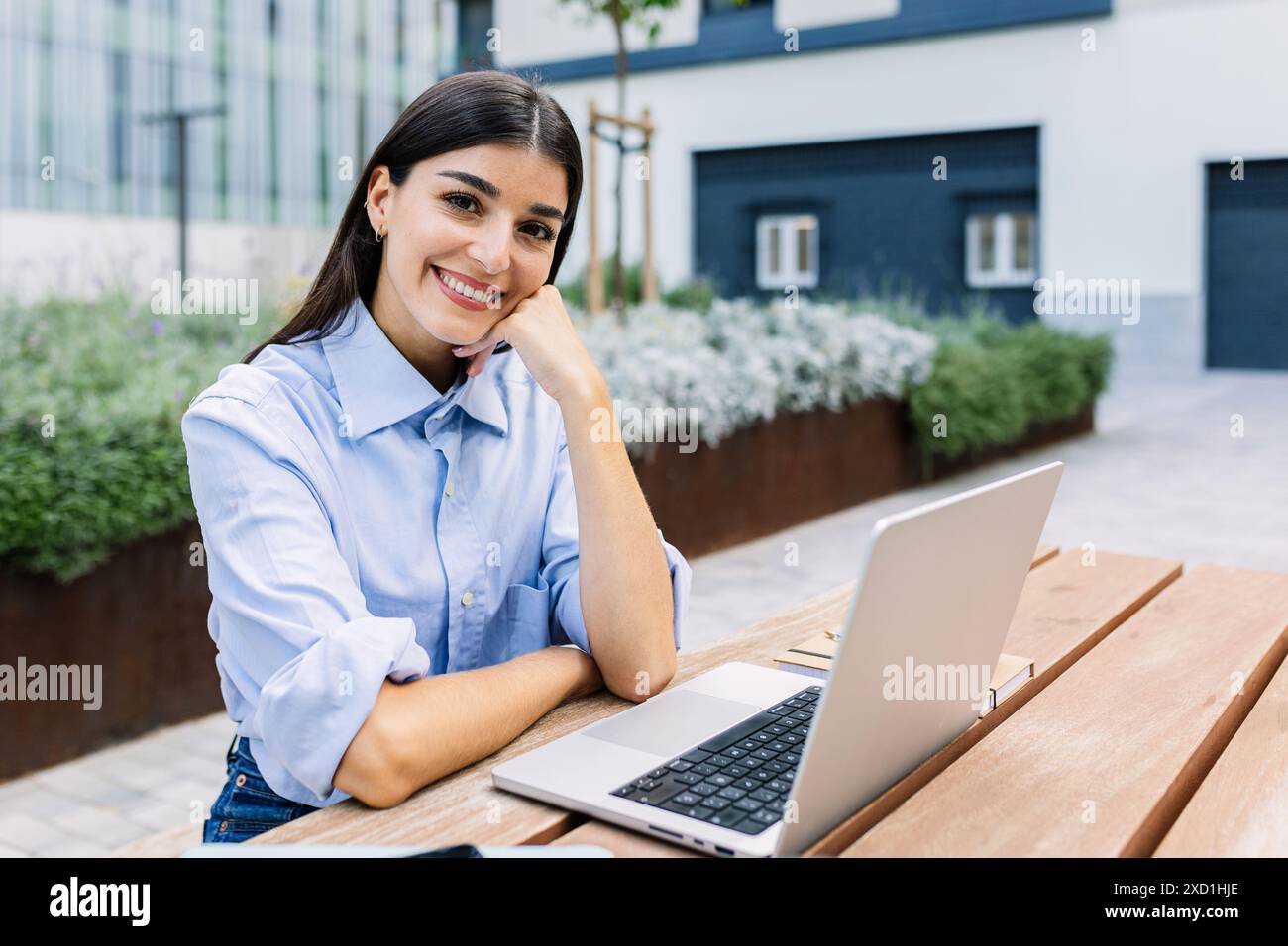 Ritratto di una donna d'affari felice e informale seduta fuori dal suo ufficio Foto Stock