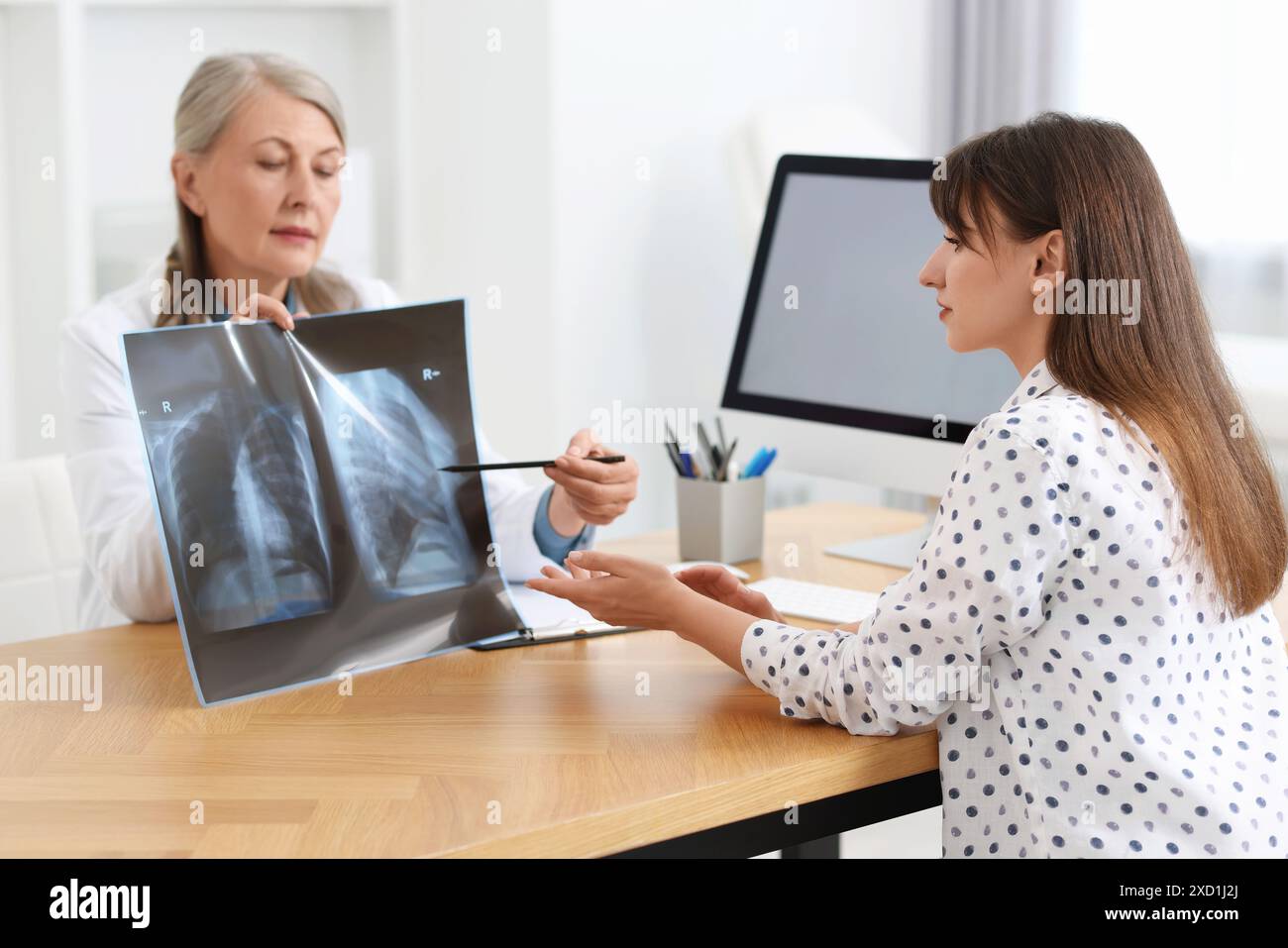 Malattia polmonare. Medico che mostra radiografia toracica al paziente in clinica Foto Stock