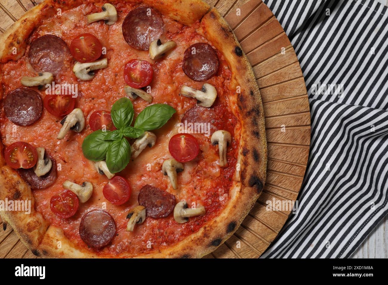 Deliziosa pizza con salame, pomodori, funghi e basilico sul tavolo, vista dall'alto Foto Stock