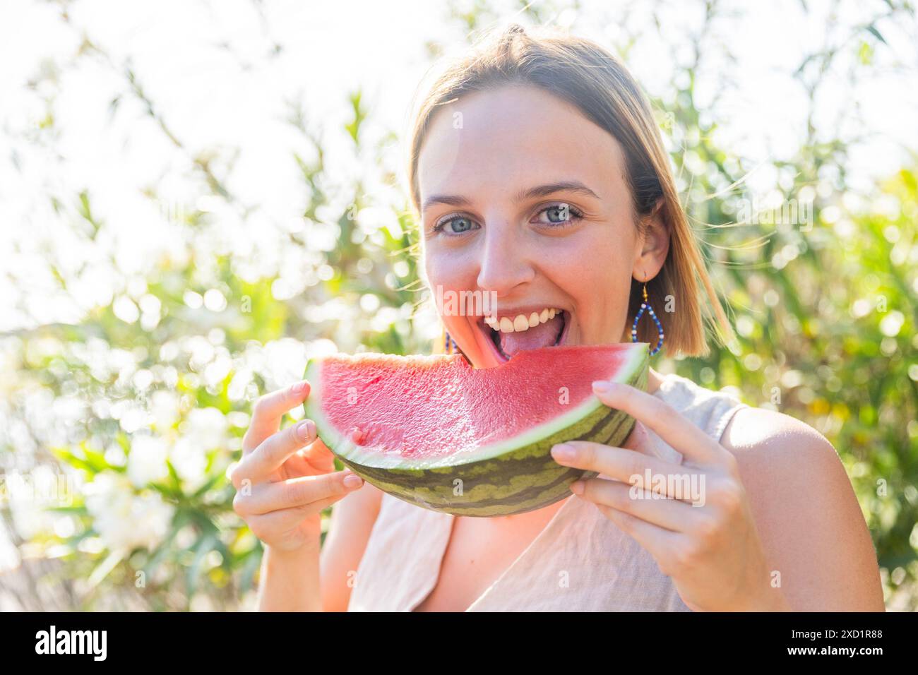 Una giovane rossa sta mangiando un anguria durante l'estate. Foto Stock