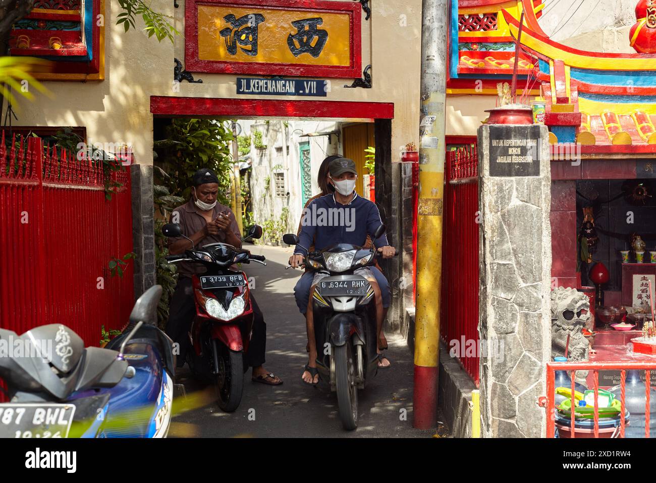 Attivita' dei residenti locali all'entrata di un vicolo con tipici ornamenti cinesi Foto Stock
