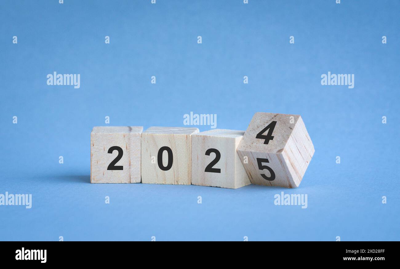 Dal 2024 al 2025, numeri su blocchi di legno. Su sfondo blu, concetto di anno nuovo. Foto Stock