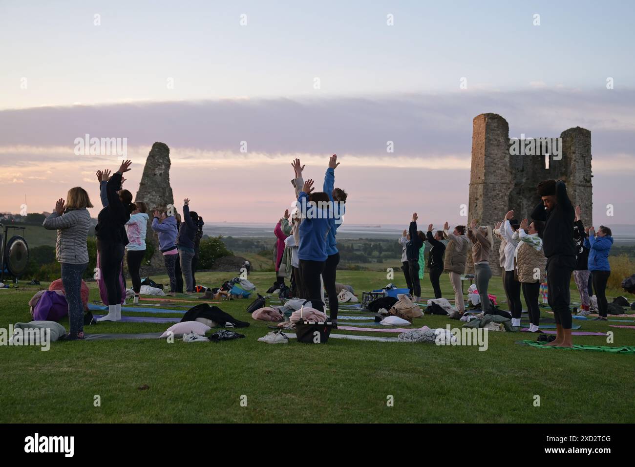 Hadleigh Essex, Regno Unito. 20 giugno 2024. Una lezione di Yoga nei terreni del Castello di Hadleigh nell'Essex nel Regno Unito saluta l'alba la mattina del solstizio d'estate. Il sole sorge alle 04:40 e tramonta alle 21:19 in quello che è il giorno più lungo dell'anno. Il periodo ufficiale del solstizio d'estate nel Regno Unito è alle 21:50 del 20 giugno 2024. Crediti: MARTIN DALTON/Alamy Live News Foto Stock