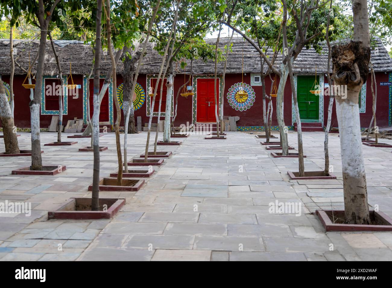 colorata e artistica casa tradizionale in teak e cespuglio con alberi verdi nel cortile di sera Foto Stock