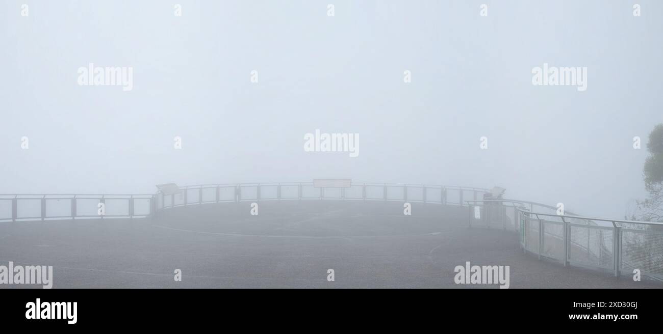 Un ampio panorama della piattaforma panoramica a Echo Point, le curve delle ringhiere protette e poi niente, le Sorelle degli alberi invisibili nella fitta nebbia Foto Stock