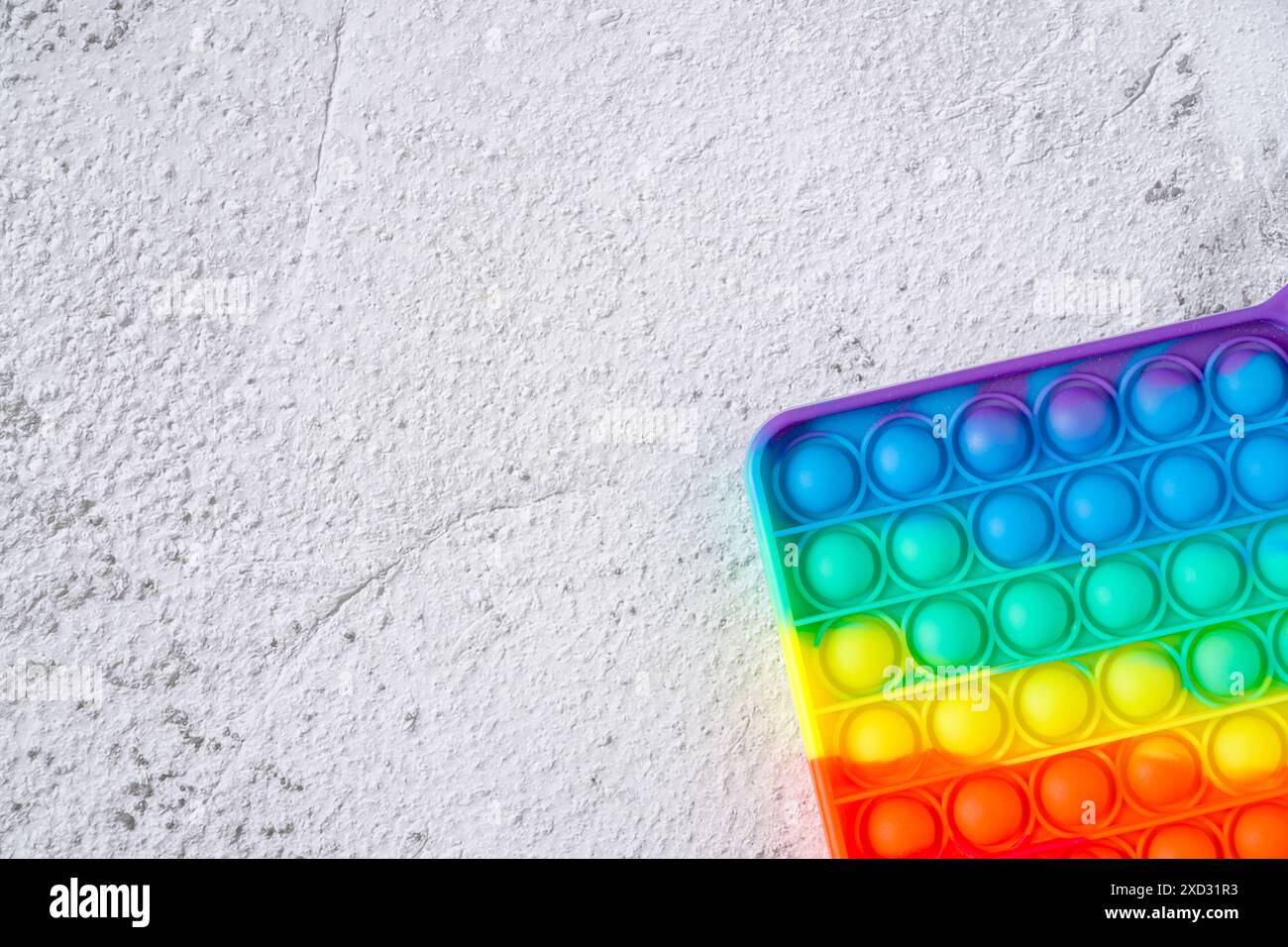 Vista dall'alto del giocattolo sensoriale anti-stress arcobaleno, premi e fallo passare su uno sfondo in pietra Foto Stock